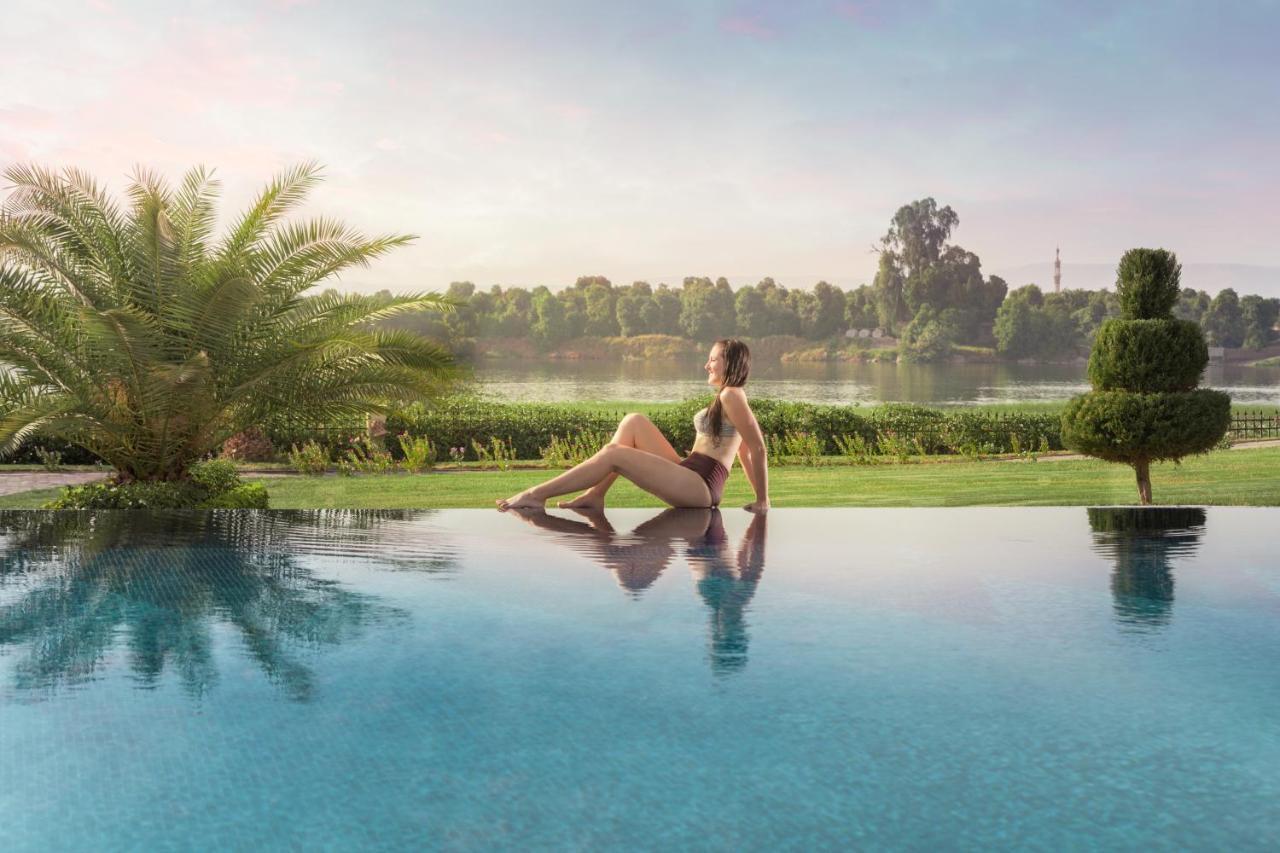 Jolie Ville Hotel & Spa Kings Island Luxor Eksteriør billede A woman sitting on the edge of a pool